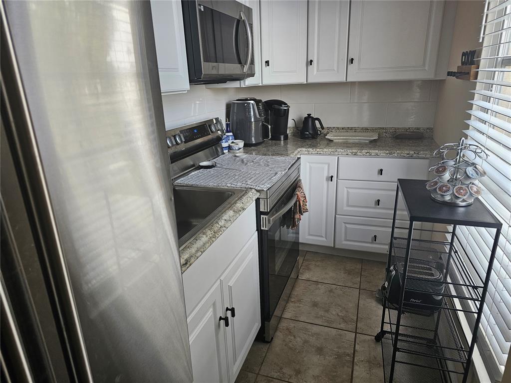 A kitchen features white cabinets, stainless steel appliances, granite countertops, and tile flooring — 915 CLUB CIRCLE, LAKESHORE, FL