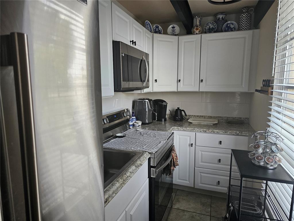 A kitchen features white cabinets, stainless steel appliances, granite countertops, and decorative plates on display — 915 CLUB CIRCLE, LAKESHORE, FL