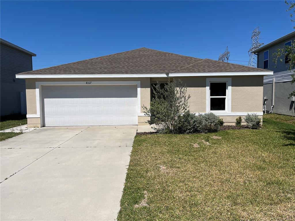 A single-story house with a beige stucco exterior, a two-car garage, and a brown roof — 4167 SAND RIDGE BOULEVARD, SPRING HILL, FL