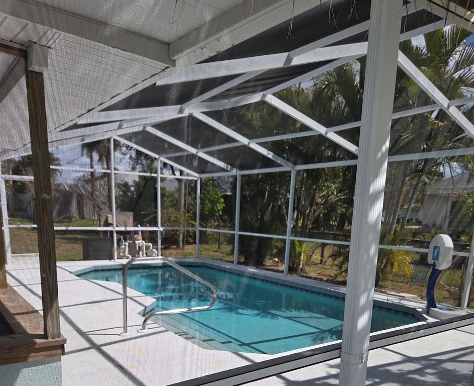 A screened-in swimming pool with a metal handrail sits on a concrete patio — 491 S VENICE BOULEVARD, VENICE, FL