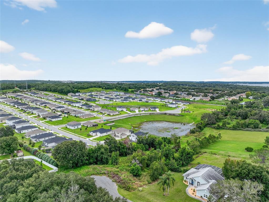 An aerial view shows a suburban neighborhood with houses surrounding a central retention pond — TBD KANUBA COURT, CLERMONT, FL