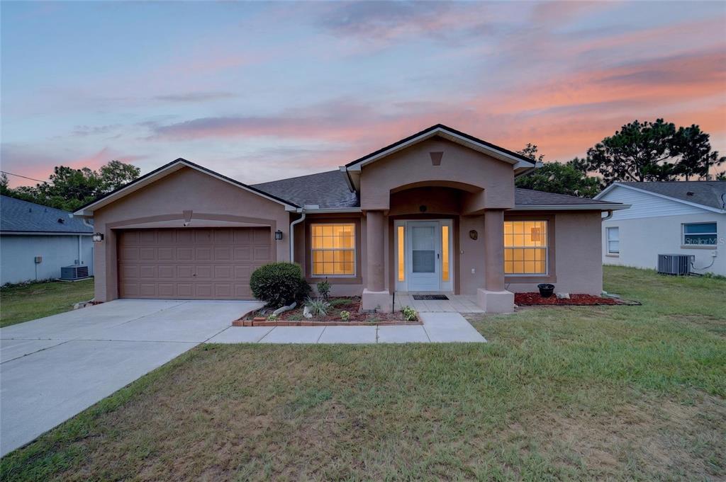A single-story house with a tan stucco exterior, a two-car garage, and a covered entryway — 5115 PECAN ROAD, OCALA, FL