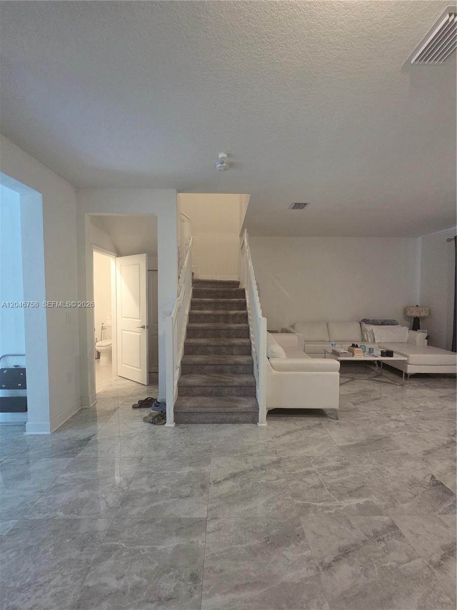 A living room features gray marble floors, a white sectional sofa, and a carpeted staircase — 21124 NE 8th Ave # 211, Miami FL 33179, MIAMI, FL