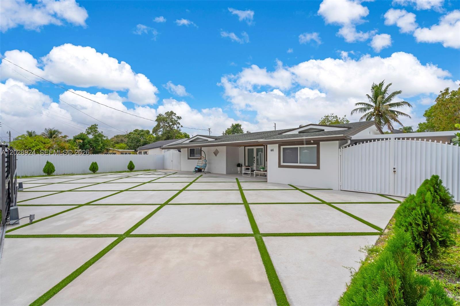 A white house features a large concrete driveway with artificial turf grid lines — 46 NE 164th St # 0, Miami FL 33162, MIAMI, FL