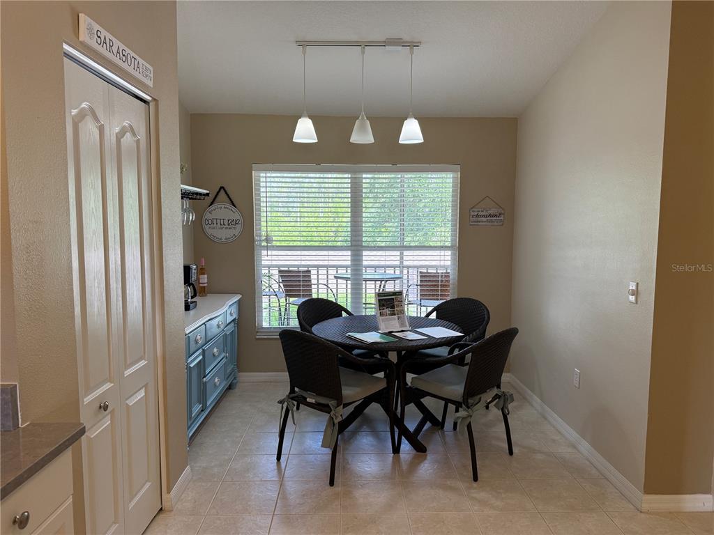 A dining area features a round table with four chairs, a blue sideboard, and pendant lighting — 5320 HYLAND HILLS AVENUE UNIT 2222, SARASOTA, FL