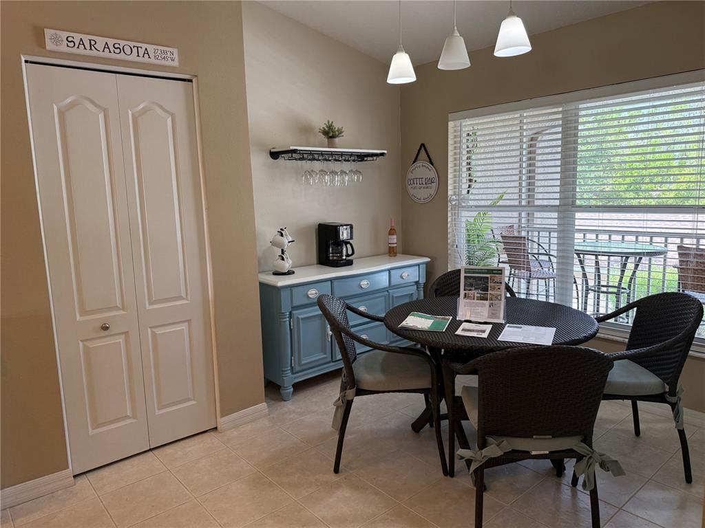 A dining area features a blue sideboard, a round table with four chairs, and pendant lighting — 5320 HYLAND HILLS AVENUE UNIT 2222, SARASOTA, FL