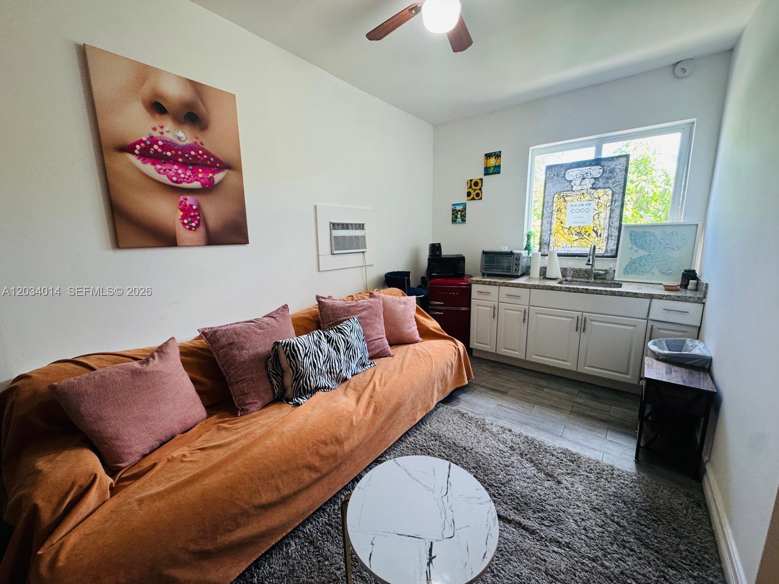 This studio apartment features a kitchenette, a sofa, and a large piece of wall art — 11 NW 47th Ter # 1B, Miami FL 33127, MIAMI, FL