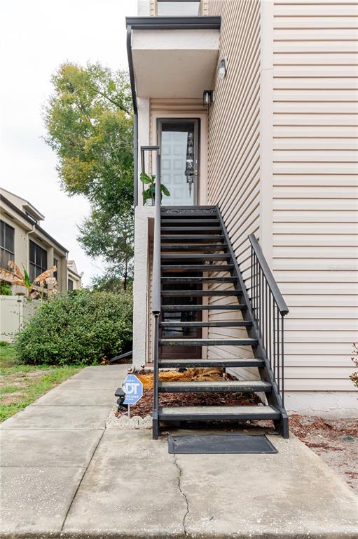 An exterior view shows a metal staircase leading to an elevated doorway with light siding — 4835 PURITAN CIRCLE UNIT 121, TAMPA, FL
