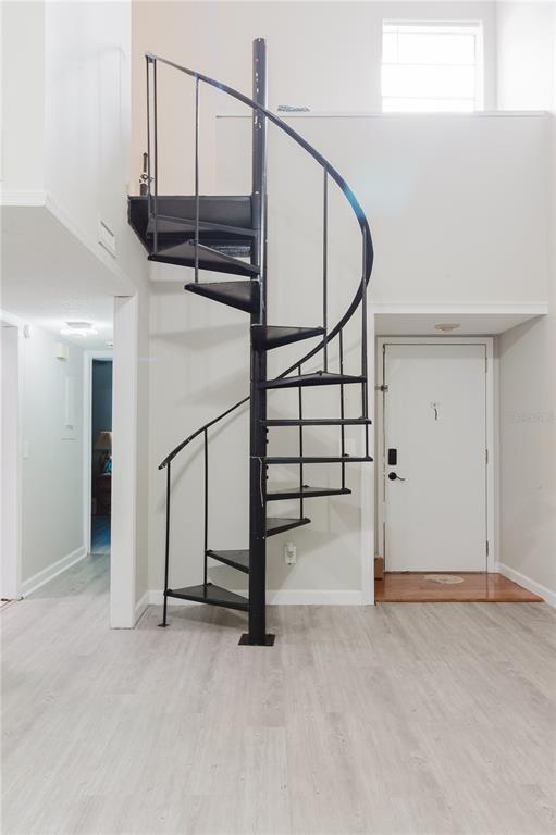 A black metal spiral staircase stands in a room with light wood-look flooring — 4835 PURITAN CIRCLE UNIT 121, TAMPA, FL