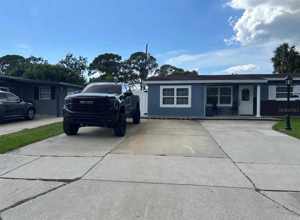 A blue single-story house with a concrete driveway and a black pickup truck parked outside — 5112 GATEWAY DRIVE, TAMPA, FL
