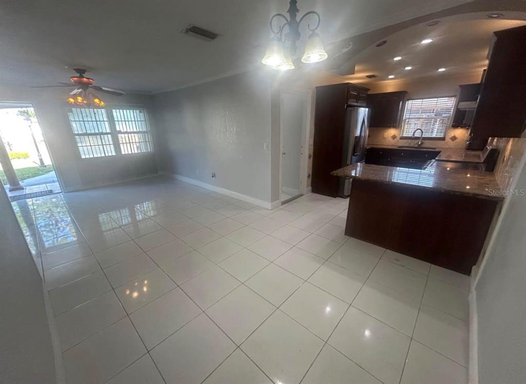 An open-concept kitchen and dining area features white tile floors and dark wood cabinetry — 5112 GATEWAY DRIVE, TAMPA, FL