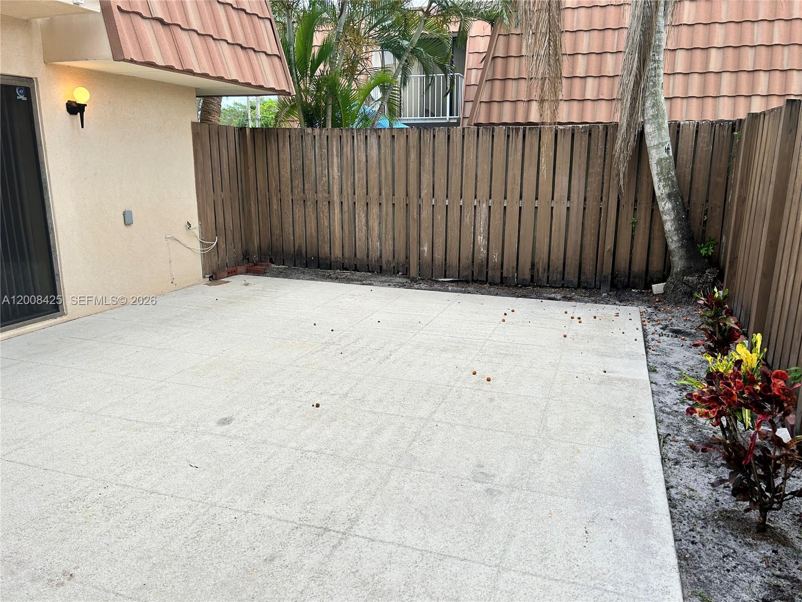 A concrete patio sits adjacent to a stucco wall and a wooden privacy fence — 736 Mill Valley Pl # 736, West Palm Beach FL 33409, WEST PALM BEACH, FL