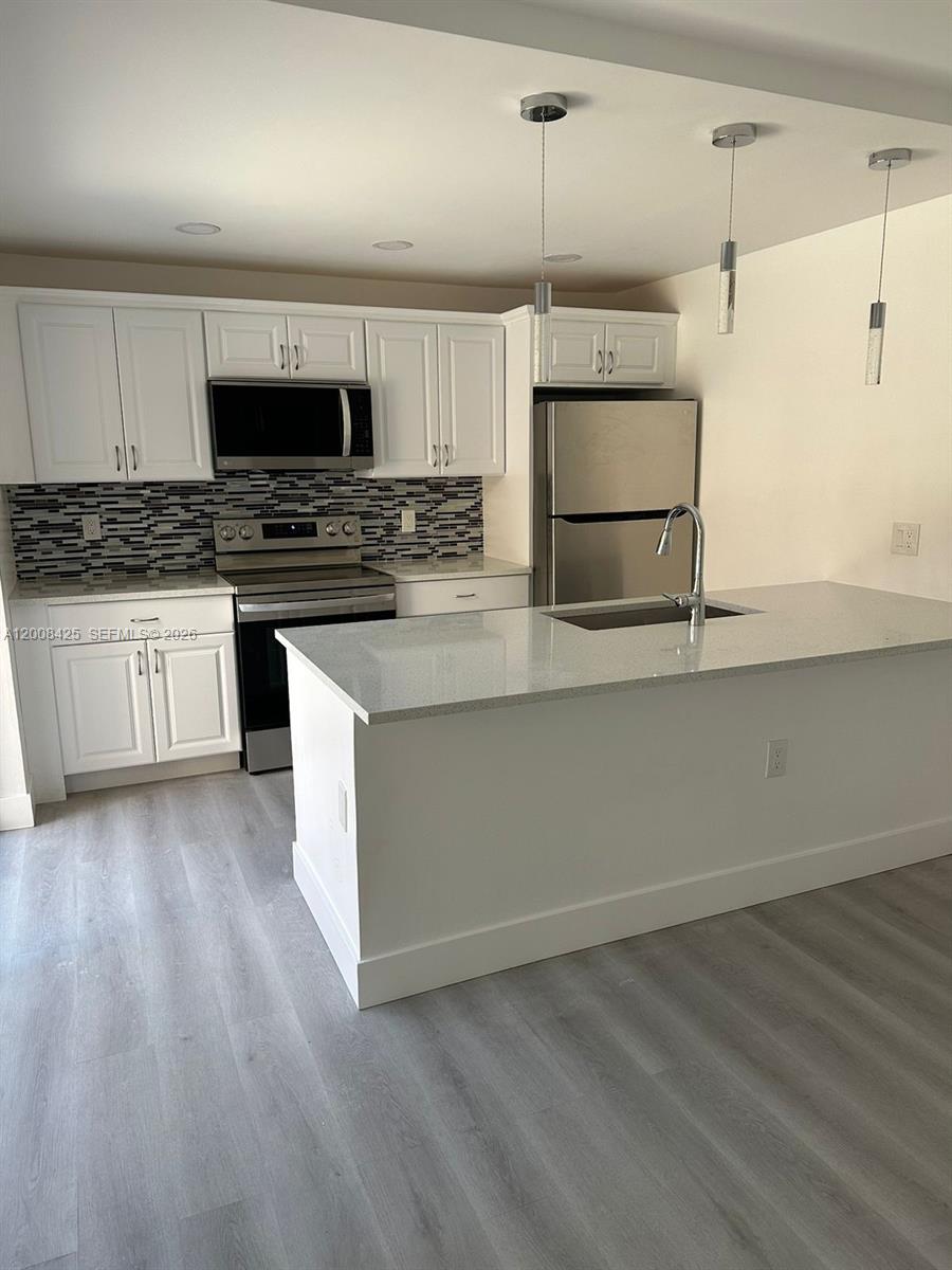 A modern kitchen features white cabinets, stainless steel appliances, and a central island with seating — 736 Mill Valley Pl # 736, West Palm Beach FL 33409, WEST PALM BEACH, FL