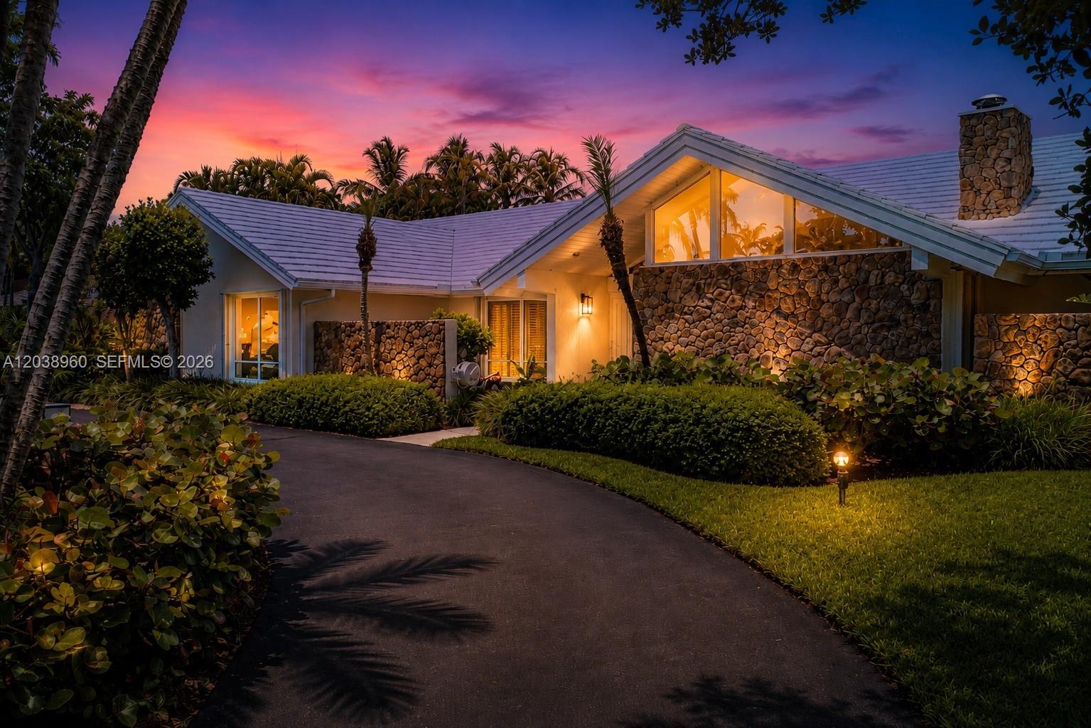 A single-story house with a stone facade, white roof, and curved driveway at sunset — 13025 SW 108th Ave, Miami FL 33176, MIAMI, FL