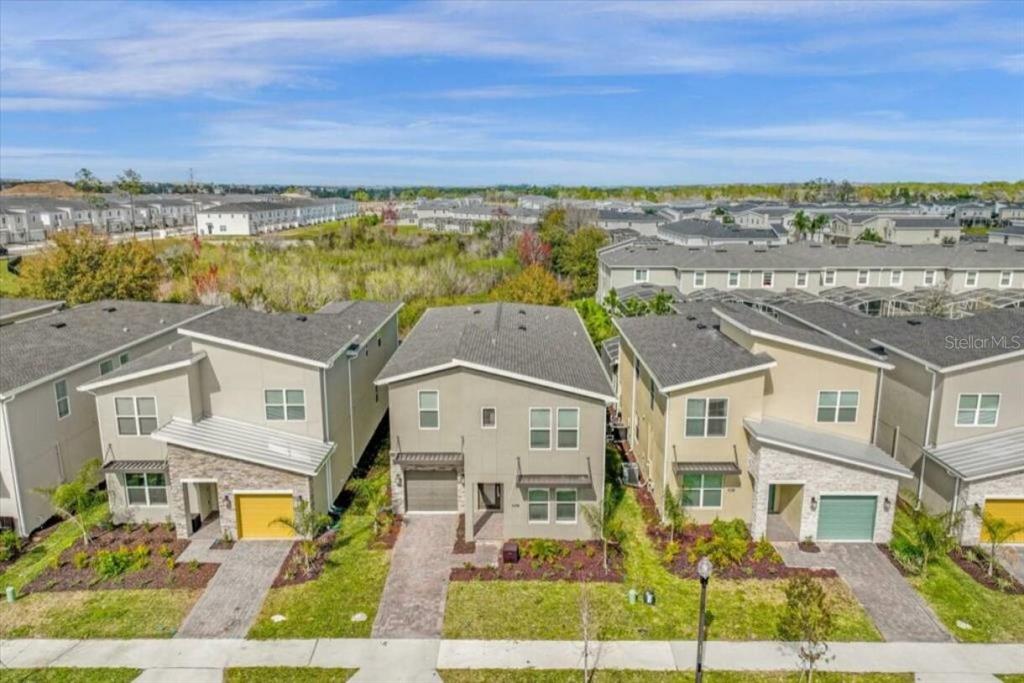 An aerial view shows three modern two-story suburban houses with driveways and small front lawns — 8967 PLAY THROUGH DR, DAVENPORT, FL