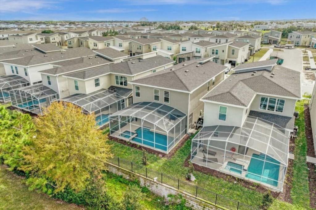 An aerial view shows several suburban houses with screened-in swimming pools and backyard fences — 8967 PLAY THROUGH DR, DAVENPORT, FL