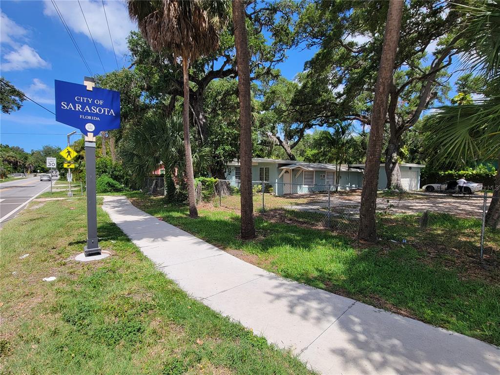 A light blue house sits behind a chain-link fence next to a City of Sarasota sign — 1375 MYRTLE STREET, SARASOTA, FL
