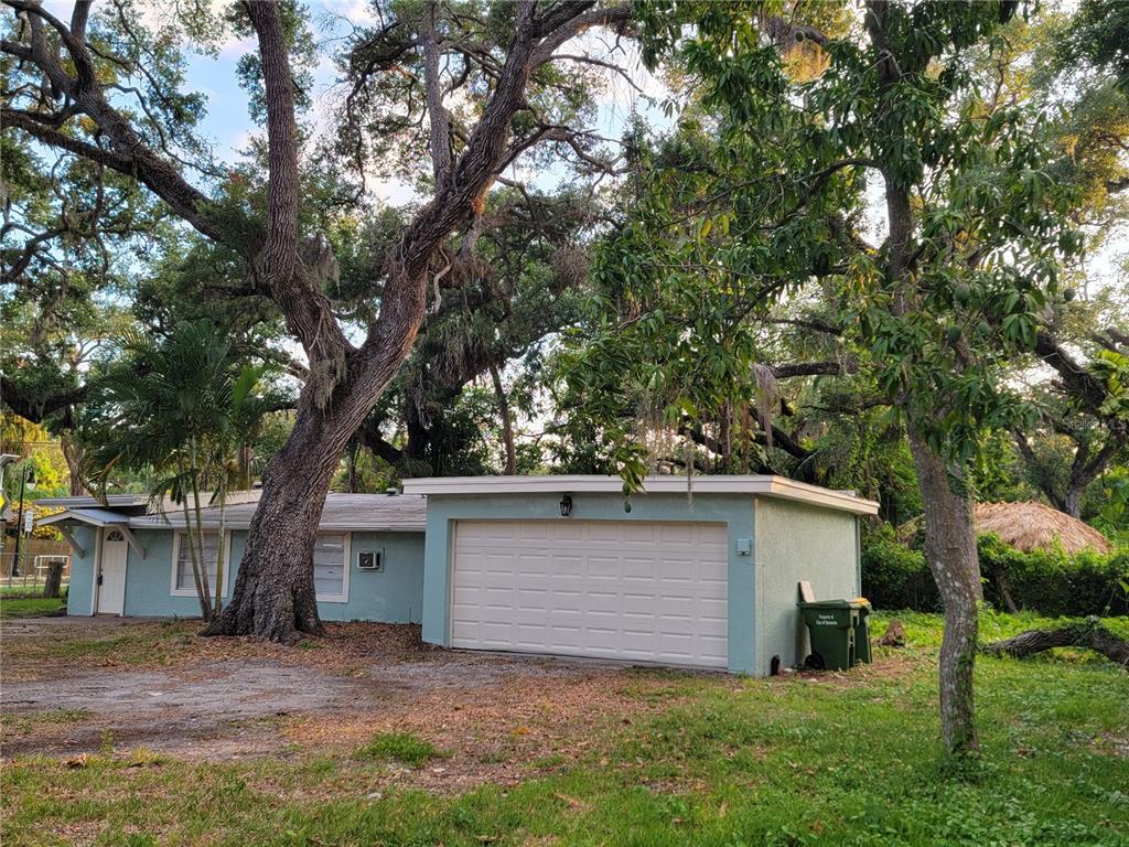 A light blue single-story house with a flat roof and an attached garage under trees — 1375 MYRTLE STREET, SARASOTA, FL