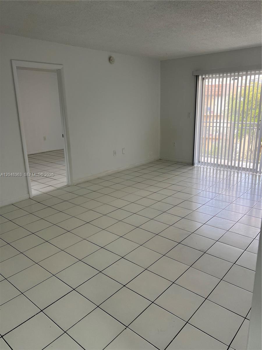 A room with white tiled floors, white walls, and a sliding glass door with blinds — 4715 NW 7th St # 2, Miami FL 33126, MIAMI, FL