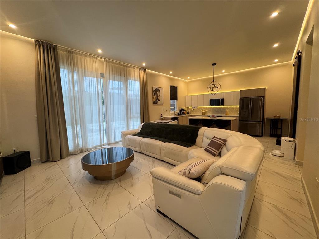A modern open-concept living room features white tile floors, a large sectional, and kitchen — 201 GUADIANA, GURABO, PR