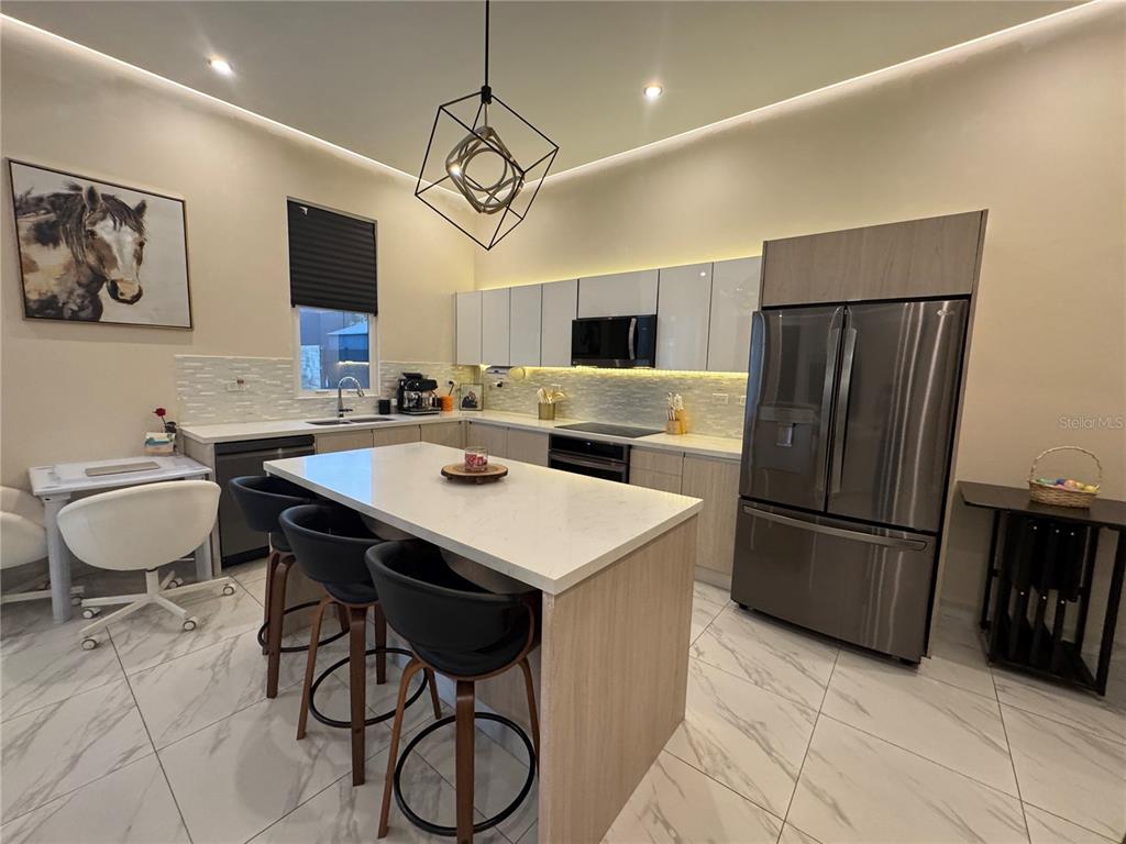 A modern kitchen features a central island, white cabinetry, stainless steel appliances, and tile flooring — 201 GUADIANA, GURABO, PR
