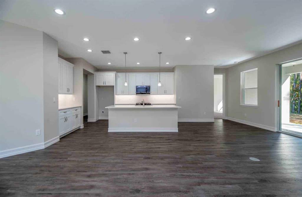 A modern kitchen with white cabinets, a central island, and dark wood-look flooring — 12418 SW 62ND PLACE, OCALA, FL