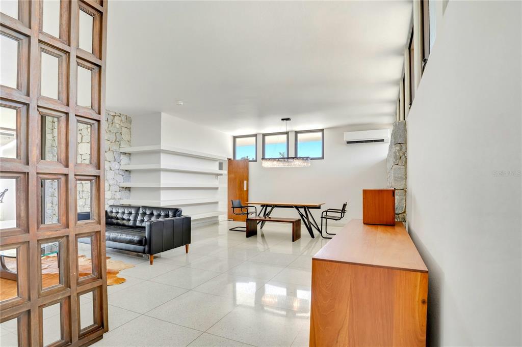 A modern living and dining area features white tile floors, stone accent walls, and a wooden screen — 176 CALLE MIMOSA, SAN JUAN, PR