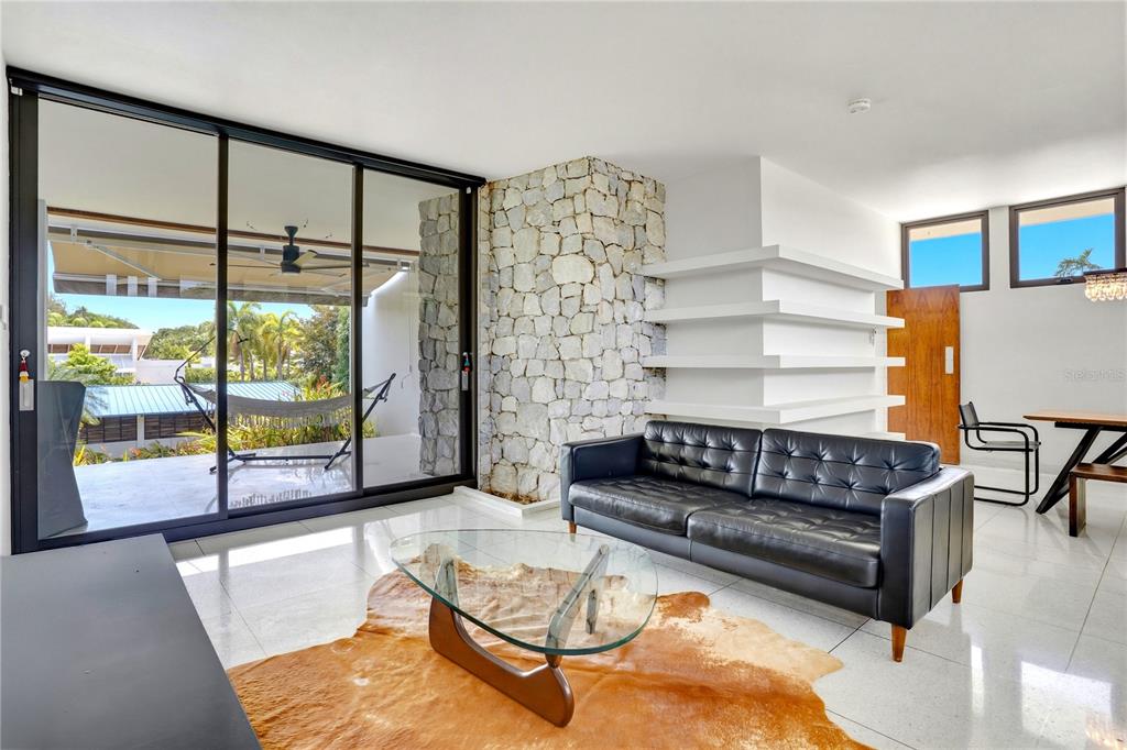 A living room features a stone accent wall, a black leather sofa, and sliding glass doors — 176 CALLE MIMOSA, SAN JUAN, PR