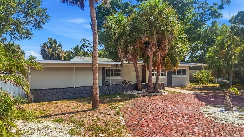 A single-story house with a brick driveway, palm trees, and a stone-accented exterior wall — 6400 PELICAN DRIVE S, ST PETERSBURG, FL