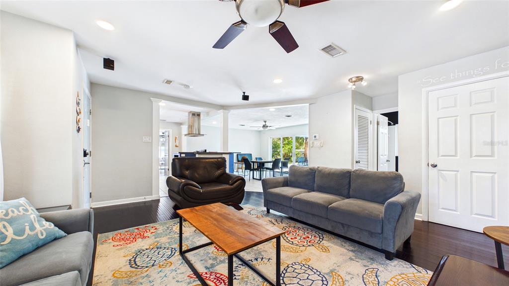 A living room features a grey sofa, a leather armchair, and a patterned area rug — 6400 PELICAN DRIVE S, ST PETERSBURG, FL