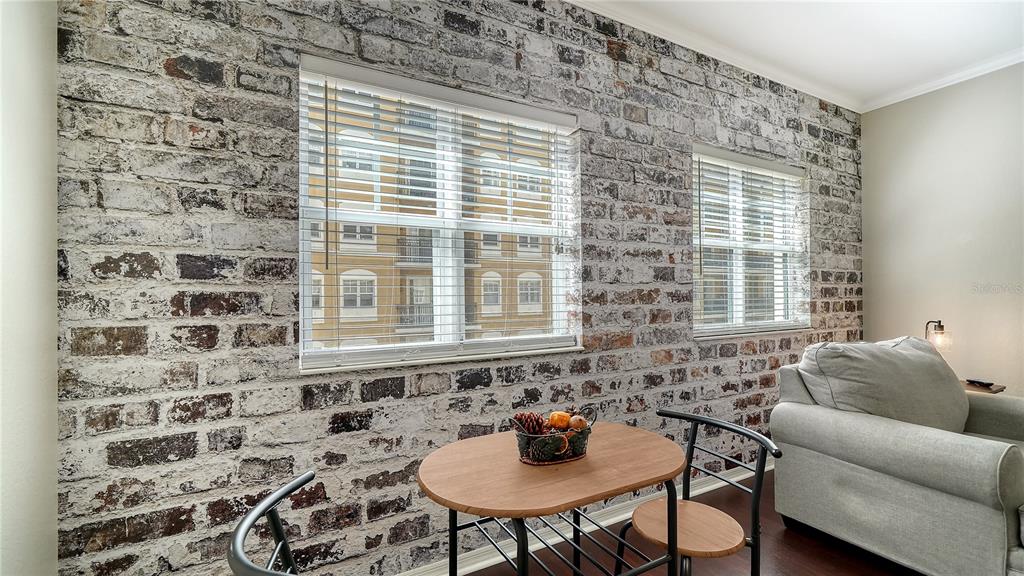 A dining area features a small wooden table, metal chairs, and a whitewashed brick wall — 1064 N TAMIAMI TRAIL UNIT 1320, SARASOTA, FL