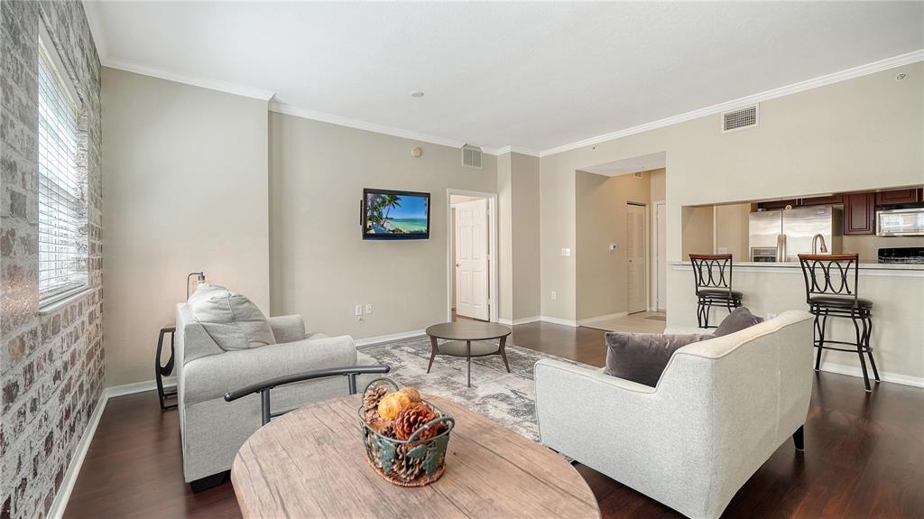 A living room with a brick accent wall, two sofas, and an open kitchen area — 1064 N TAMIAMI TRAIL UNIT 1320, SARASOTA, FL