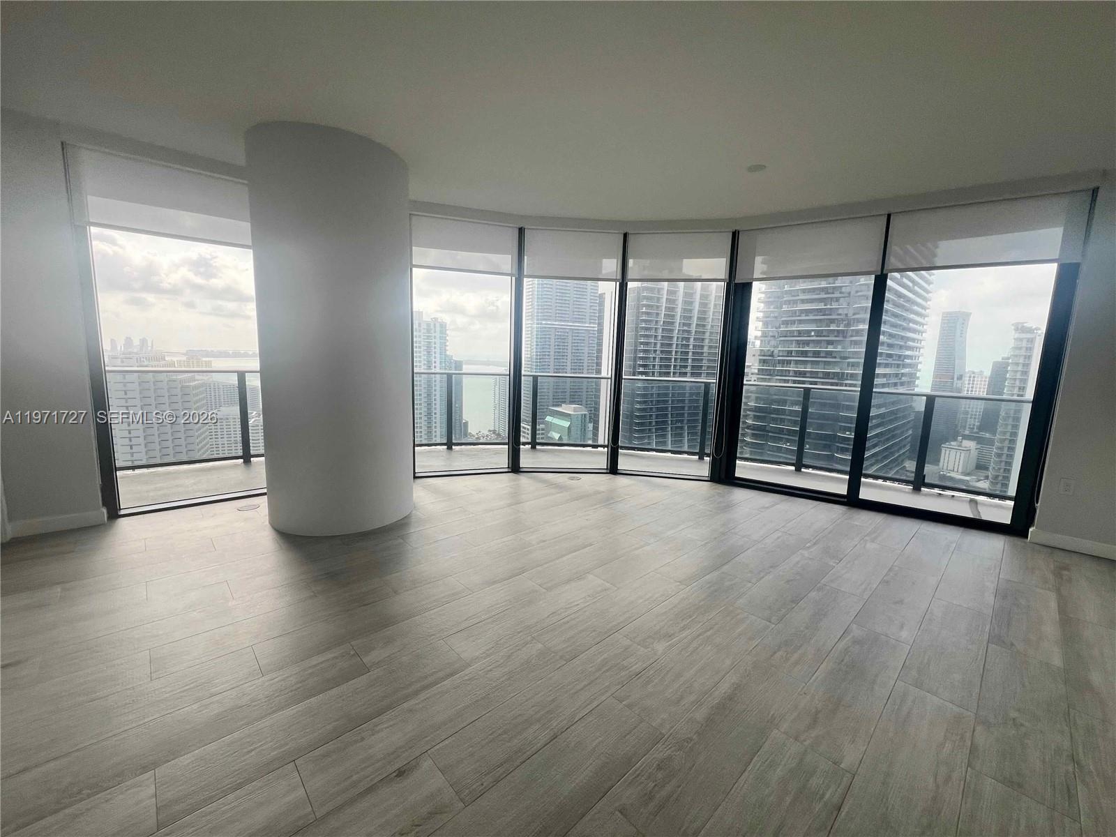 An empty room with light wood-look flooring, a large structural column, and floor-to-ceiling windows — 45 SW 9th St # 3703, Miami FL 33130, MIAMI, FL