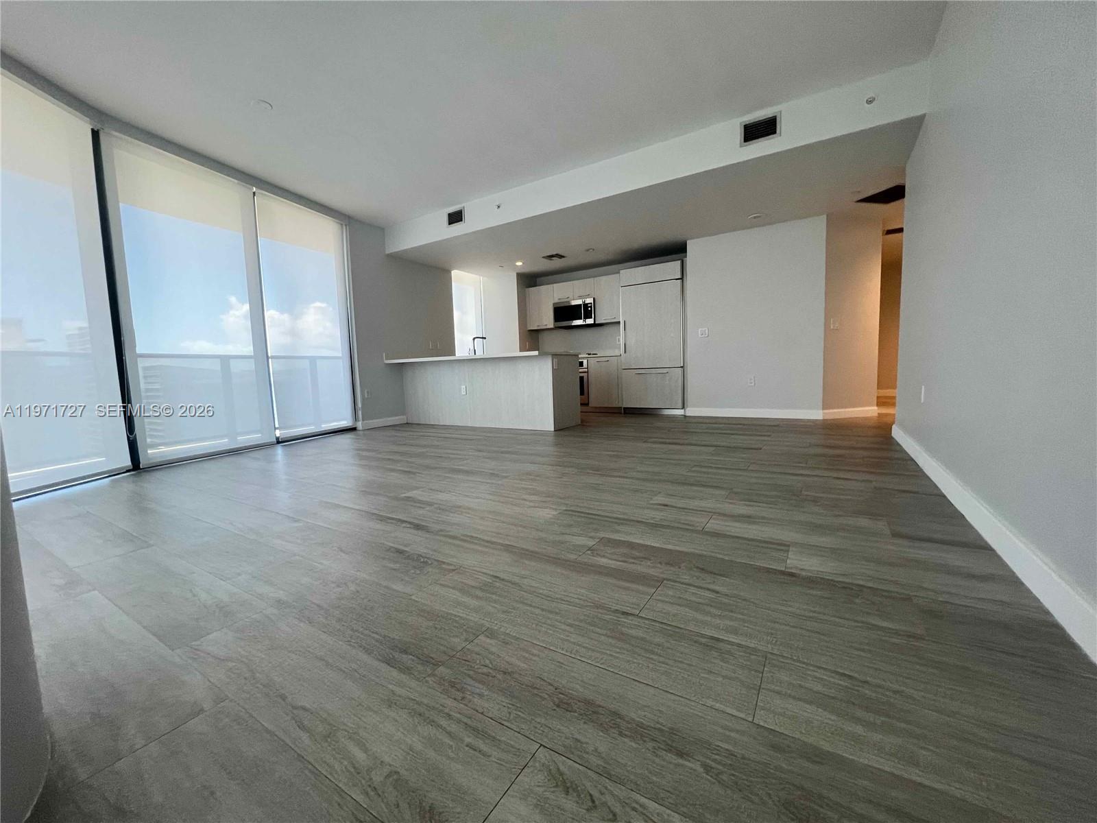 An open-concept living area features light wood-look flooring, a modern kitchen, and floor-to-ceiling windows — 45 SW 9th St # 3703, Miami FL 33130, MIAMI, FL
