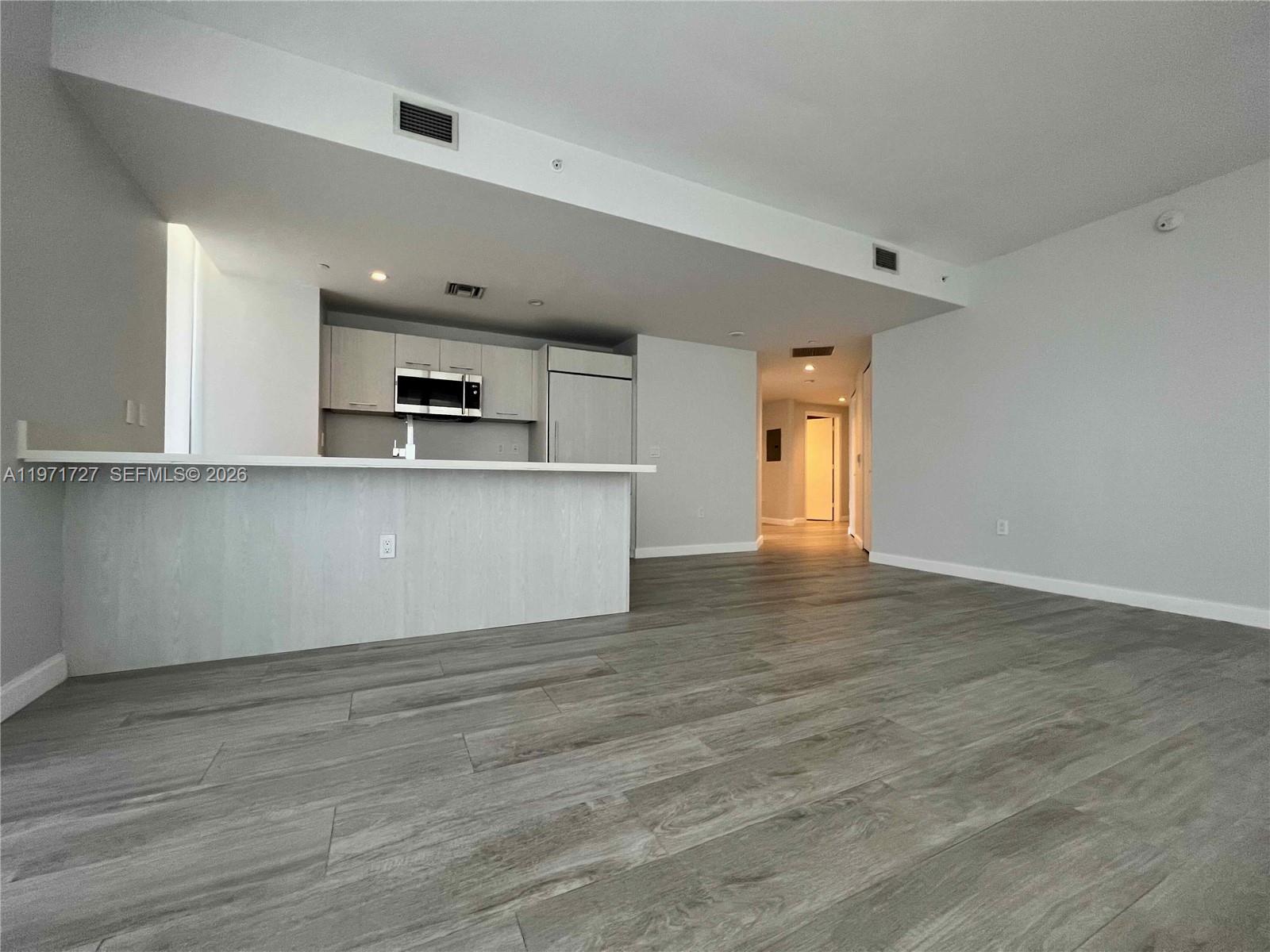 An open-concept kitchen with light wood cabinetry and a breakfast bar overlooks a living area — 45 SW 9th St # 3703, Miami FL 33130, MIAMI, FL