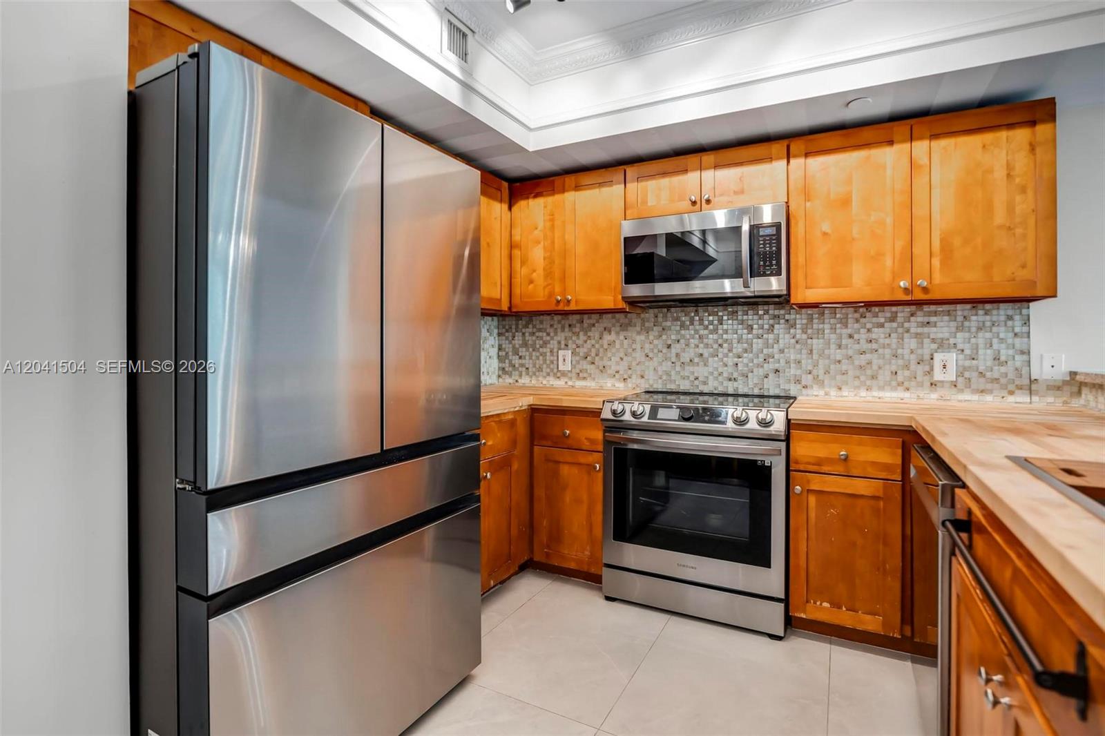 A kitchen features stainless steel appliances, wooden cabinets, and a tiled backsplash — 1723 SW 2nd Ave # 607, Miami FL 33129, MIAMI, FL