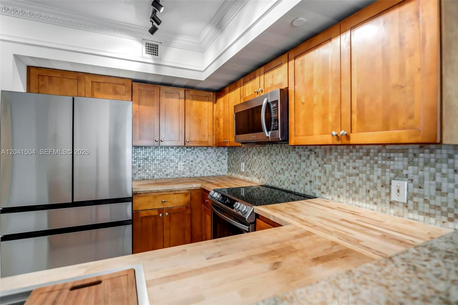 A kitchen features wooden cabinets, butcher block countertops, a stainless steel refrigerator, and mosaic tile — 1723 SW 2nd Ave # 607, Miami FL 33129, MIAMI, FL