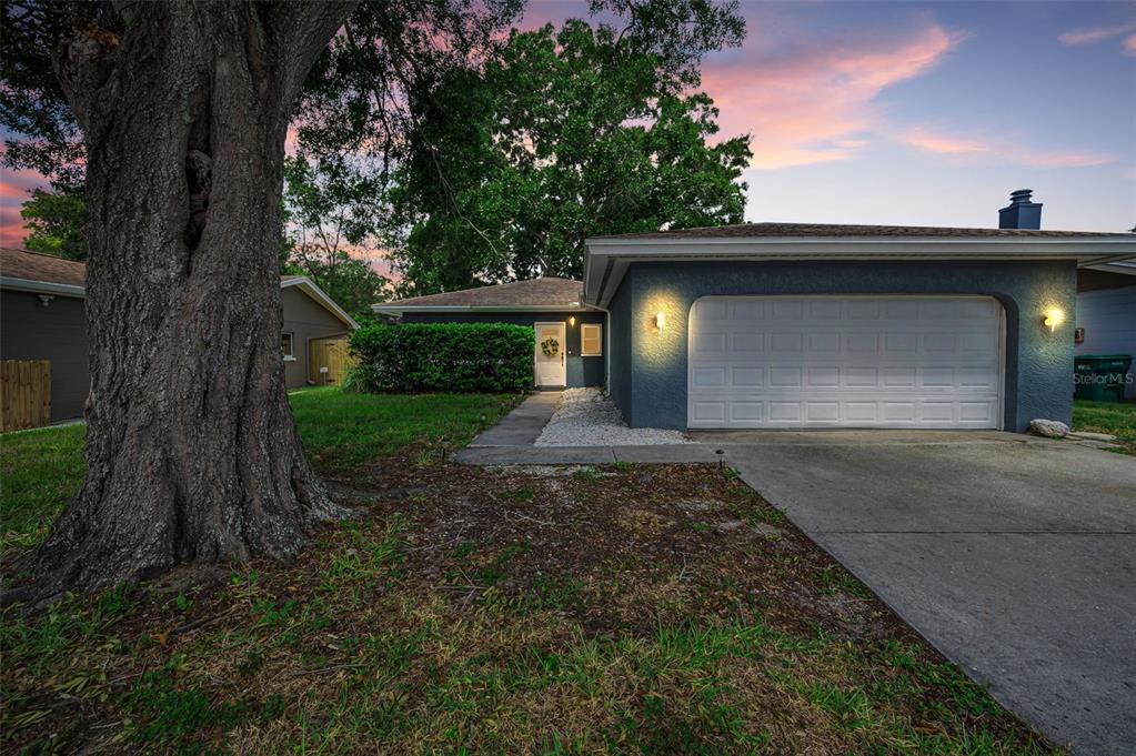 A single-story house with a blue exterior, a two-car garage, and a large front tree — 1760 E ORANGESIDE ROAD, PALM HARBOR, FL
