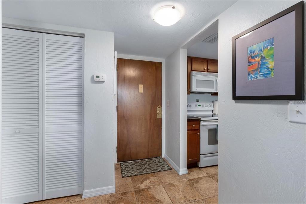 A view of an entryway with a wooden door, tiled floor, and an adjacent kitchen — 3600 S OCEAN SHORE BOULEVARD UNIT 423, FLAGLER BEACH, FL