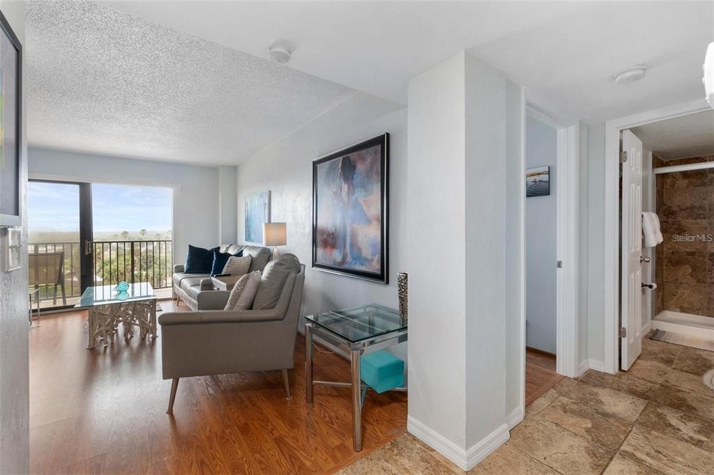 A living room with wood flooring, a glass coffee table, and a view of the outdoors — 3600 S OCEAN SHORE BOULEVARD UNIT 423, FLAGLER BEACH, FL