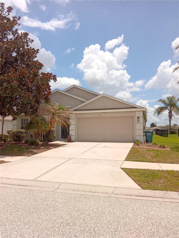 A single-story suburban house features a two-car garage, a concrete driveway, and a front lawn — 7724 OUTERBRIDGE STREET, WESLEY CHAPEL, FL