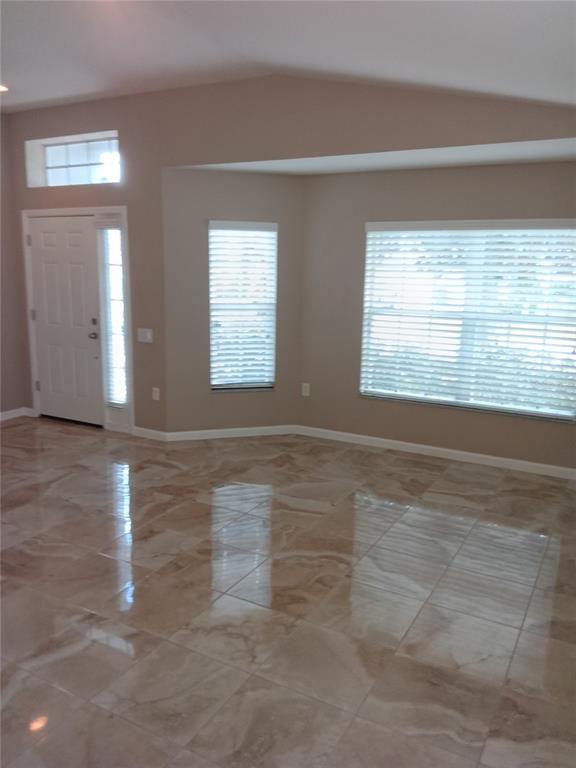 An interior view of a room with beige walls, large windows, and polished tile flooring — 7724 OUTERBRIDGE STREET, WESLEY CHAPEL, FL