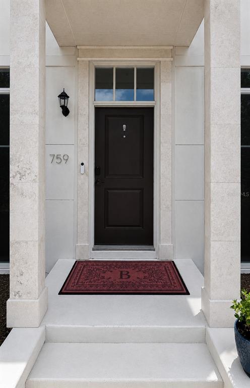 A dark front door with a transom window sits between two stone pillars — 759 LAKE BALDWIN LANE, ORLANDO, FL