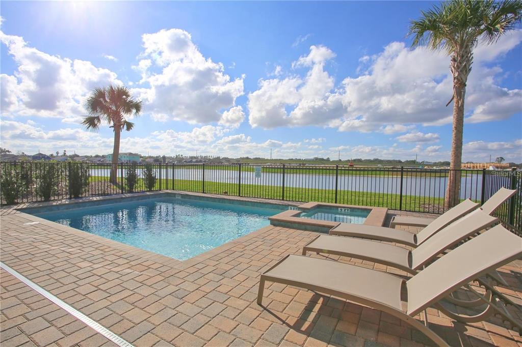 A swimming pool and hot tub sit on a brick patio overlooking a lake — 8145 SURF STREET, KISSIMMEE, FL