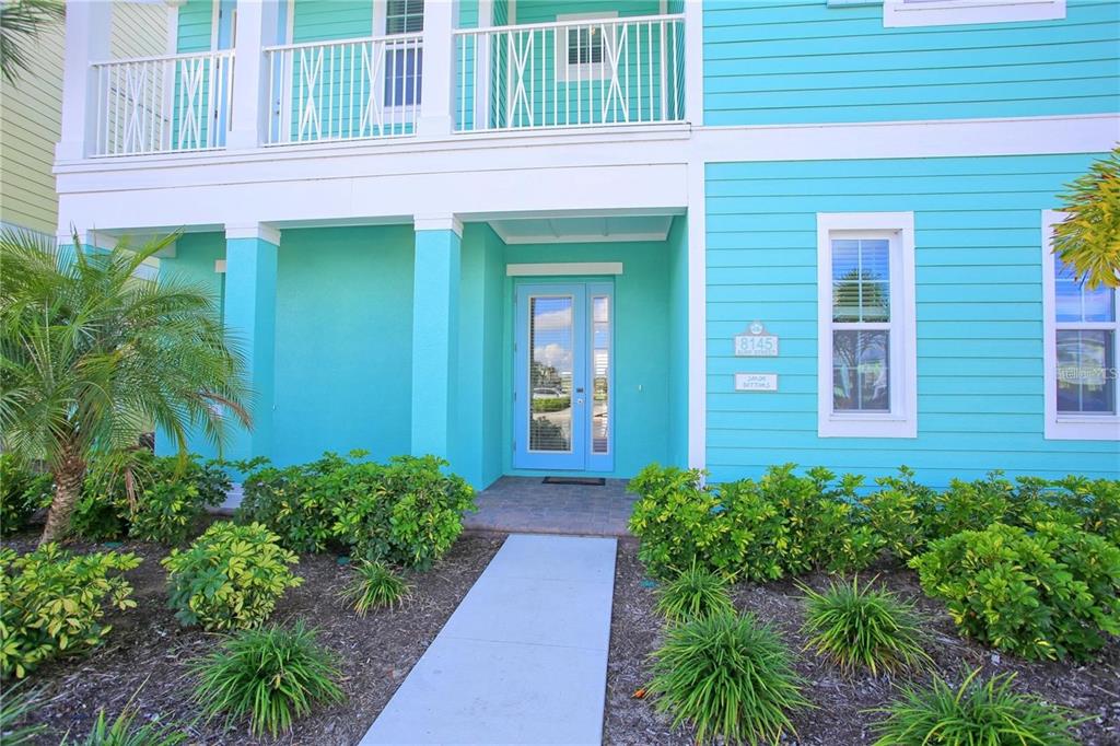 A bright turquoise two-story house features a front entrance with a glass-paned door — 8145 SURF STREET, KISSIMMEE, FL