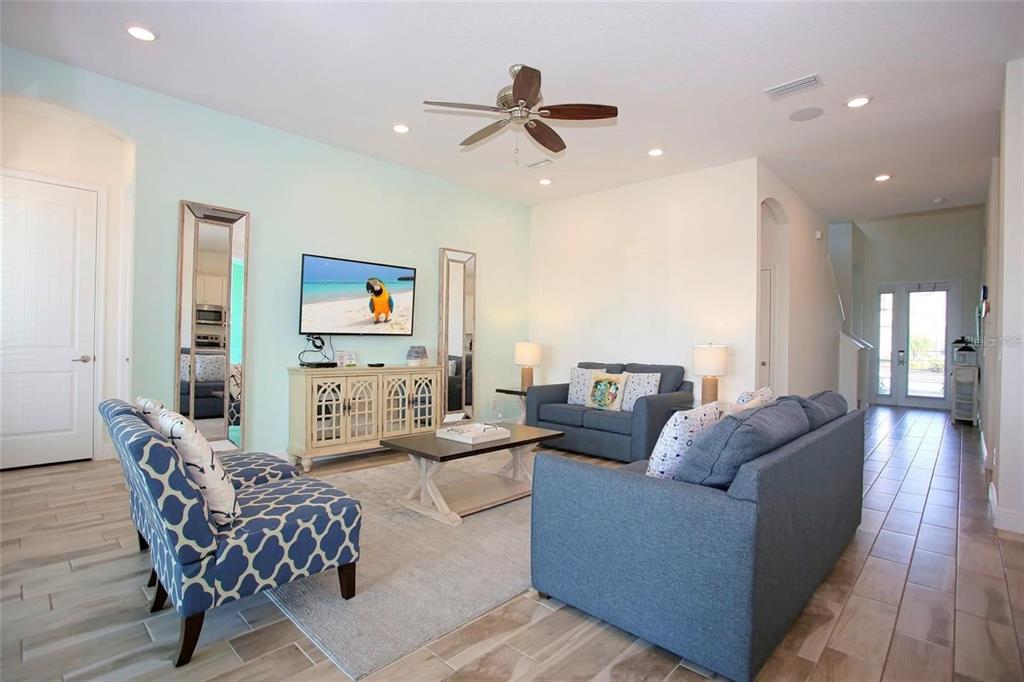 A living room features light blue walls, a ceiling fan, two sofas, and tile flooring — 8145 SURF STREET, KISSIMMEE, FL