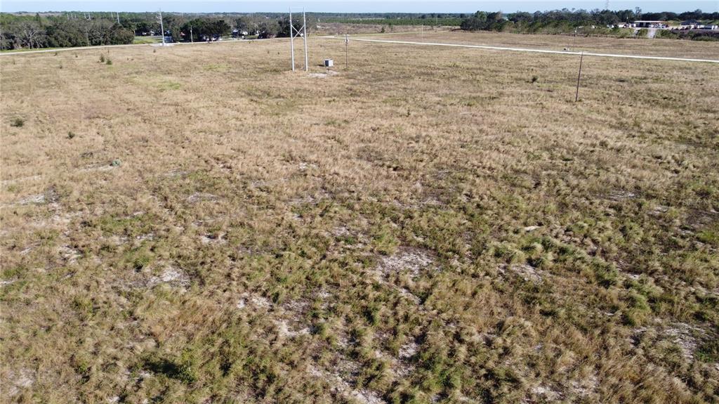 An aerial view of a large, flat, grassy vacant lot with utility poles — 7655 CR 17 S, SEBRING, FL