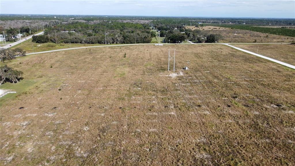 An aerial view shows a large, flat, grassy vacant lot with utility poles and roads — 7655 CR 17 S, SEBRING, FL