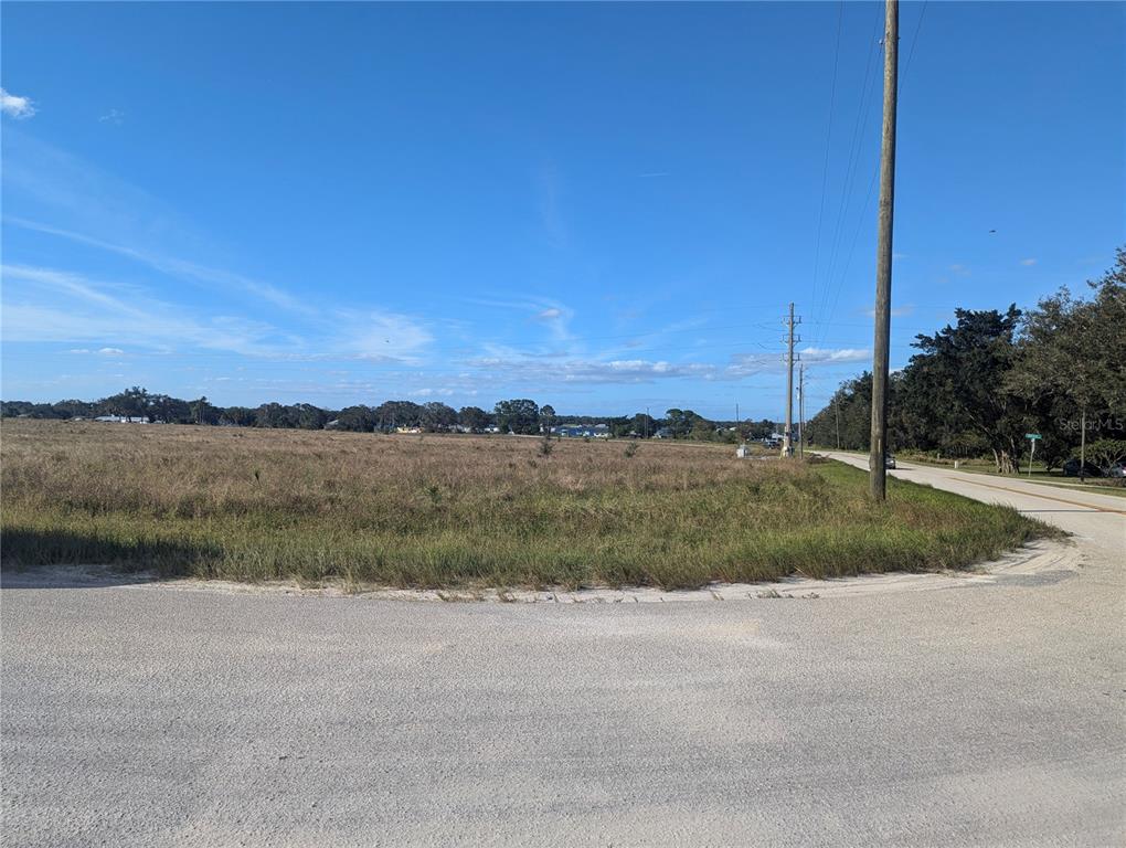 A large, flat, grassy vacant lot sits next to a paved road under a blue sky — 7655 CR 17 S, SEBRING, FL