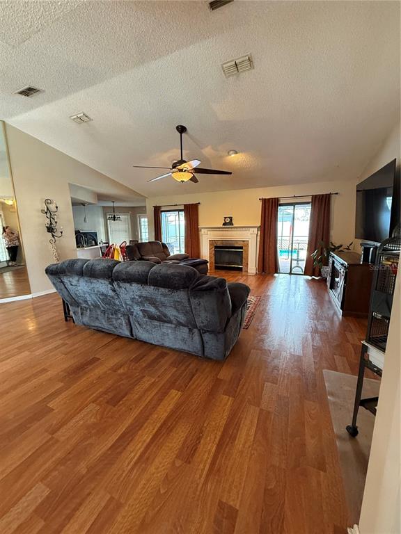 A living room features wood-look flooring, a vaulted ceiling, a fireplace, and a ceiling fan — 9231 ELDRIDGE ROAD, SPRING HILL, FL